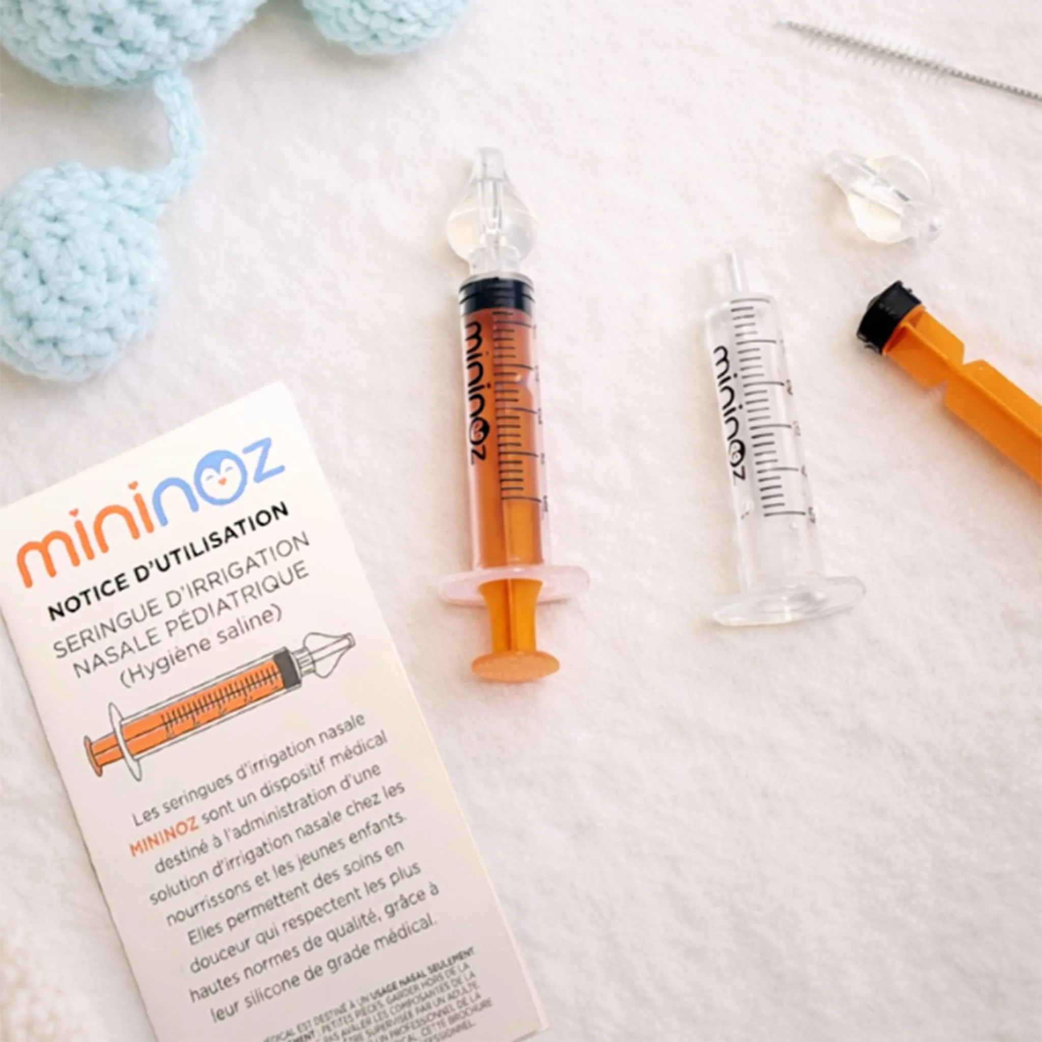 Seringues Mininoz et notice d'utilisation posées sur une couverture